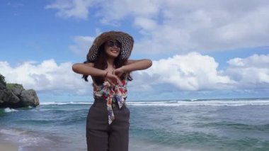 Asyalı bir kadının askılı bluz giymesi ağır çekim. Yaz tatilinde, öğle vakti plajda tatil yapmak için çok heyecanlı.