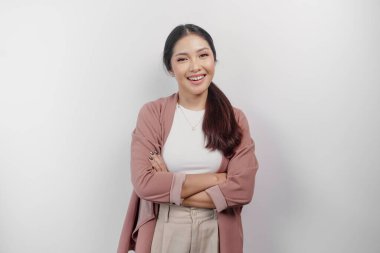 Kendine güvenen, gülümseyen, kollarını kavuşturup beyaz arka planda izole edilmiş kameraya bakan hırka giyen Asyalı bir kadın.