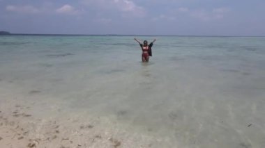 Asyalı bir kadının bikini giyip Endonezya 'nın Karimunjawa plajında eğlenceli bir tatil geçirdiği hava manzarası.