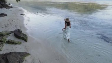 Elbise giyen Asyalı bir kadının Karimunjawa Adaları, Jepara, Endonezya 'daki Bobby Sahili' nde eğlendiğini görüyoruz. Uzak Ada, mercan resifleri, beyaz kumlu plajlar.