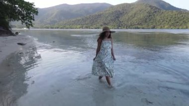 Elbise giyen Asyalı bir kadının Karimunjawa Adaları, Jepara, Endonezya 'daki Bobby Sahili' nde eğlendiğini görüyoruz. Uzak Ada, mercan resifleri, beyaz kumlu plajlar.
