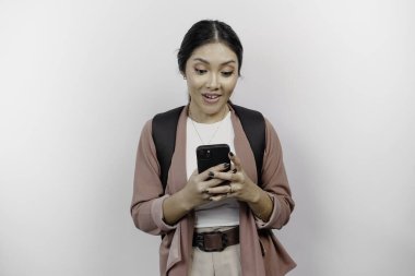 Şok olmuş genç bir Asyalı kız hırka giyiyordu. Elinde çanta ve cep telefonu vardı. Ağzını sonuna kadar açık tutuyordu..