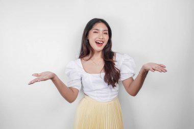 Neşeli bir Asyalı kadın beyaz arka planla izole edilmiş fotokopi alanını işaret ediyor..