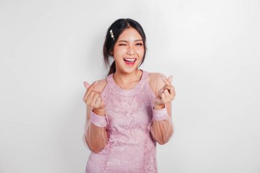 Pembe elbise giyen genç bir Asyalı kadın hassas duygular hissediyor, kalp hareketlerini şekillendiriyor aşkını ifade ediyor..