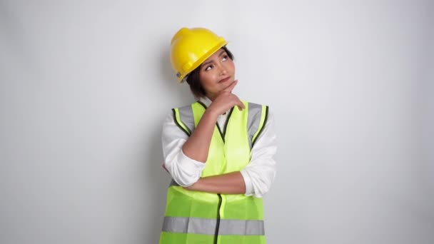 一位头戴安全帽 身穿防弹背心的有思想的年轻女工正在考虑一个关于复制空间的想法 这个想法被白色背景隔离了 劳工日的概念 — 图库视频影像