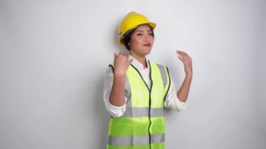Genç kadın miğfer ve yelek giyip hoparlör kullanıyor ve elleri beyaz arka planda izole bir şekilde el kol hareketi yapıyor. İşçi Bayramı konsepti.