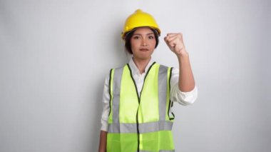 Genç kadın miğfer ve yelek giyip hoparlör kullanıyor ve elleri beyaz arka planda izole bir şekilde el kol hareketi yapıyor. İşçi Bayramı konsepti.