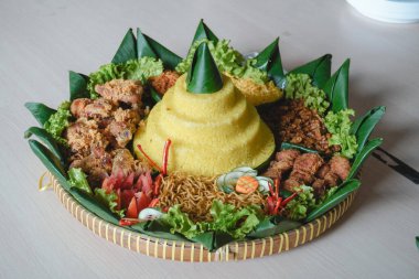 Nasi Tumpeng, beyaz arka planda izole edilmiş geleneksel Java yemekleri. Endonezya rijstafeli sarı pirinç. Bağımsızlık kutlamaları için ülkenin çeşitli bölgesel mutfaklarından mezeler..