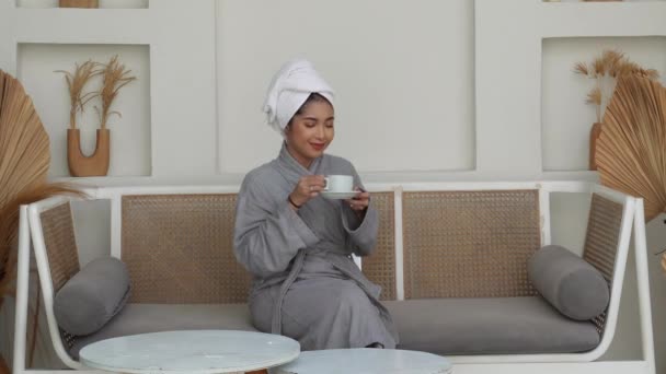 Młoda Azjatka Sącząca Poranną Kawę Lub Herbatę Filiżance Siedząca Kanapie Filmiki Stockowe bez tantiem
