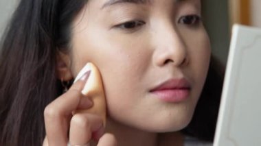 Makyaj fırçası ve puf kullanarak makyaj yapan güzel Asyalı bir kadının yakın plan portresi. Takılmaya hazırlanıyor. Güzellik ipuçları, güzellik vlogger konsepti