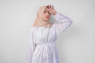 Üzgün Asyalı tesettürlü Müslüman kadın stresli ve depresif görünüyor ya da sıcak hava ve oruç yüzünden baş ağrısı çekiyor