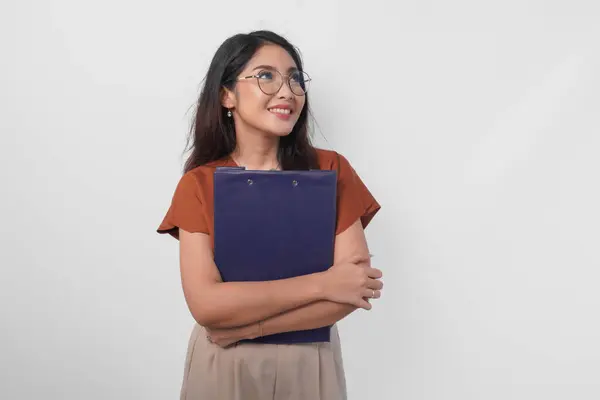 白い背景で孤立しながらドキュメントブックレポートを保持している茶色のシャツを着ている若いアジアの女性 ロイヤリティフリーのストック画像