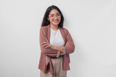 Gülümseyen Asyalı genç bir kadın kolları bağlı duran gözlüklü beyaz arka planda izole edilmiş kendine güvenen bir ifadeyle..