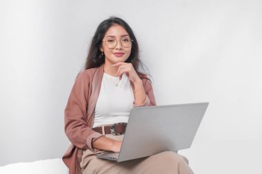 Düşünceli genç Asyalı iş kadını dizüstü bilgisayarla oturmuş beyaz arka planla izole edilmiş işi düşünüyor..