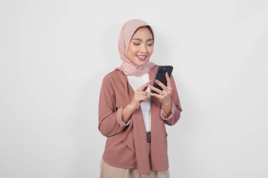 Güzel Asyalı Müslüman kadın tesettürlü elinde akıllı bir telefon ve beyaz arkaplan ile izole edilmiş bir mesaj tutuyor..