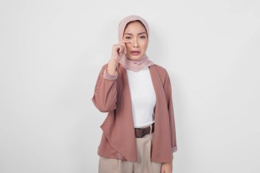 Üzgün, Asyalı, tesettürlü, ağlayan ve beyaz arka planda gözyaşlarını silen güzel bir Müslüman kadın..