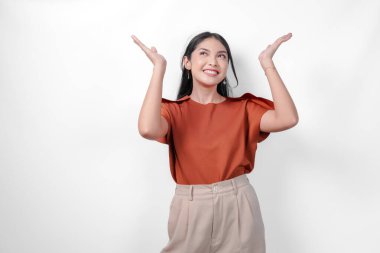 Kahverengi gömlekli ve kahverengi pantolonlu heyecanlı genç Asyalı kadın beyaz arka planla izole edilmiş fotokopi odasını sunuyor..