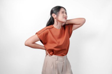 Kahverengi gömlekli yorgun bir Asyalı kadın acı çekiyor, boynundaki kas spazmı izole edilmiş beyaz arka plan..