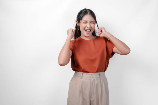 Joyful young Asian woman in a brown shirt with happy successful expression. Concept of happiness and excitement. — Stock Image Joyful Young Asian Woman Brown Shirt Happy Successful Expression Concept Royalty Free Stock Photos