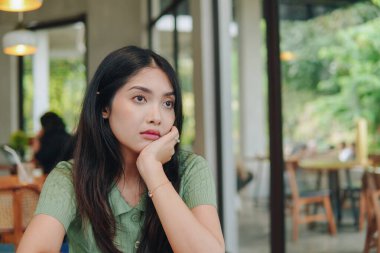 Bir kadın elleri ve çenesini destekleyen bir masada oturuyor, derin düşüncelere dalmış hayal kuruyor..