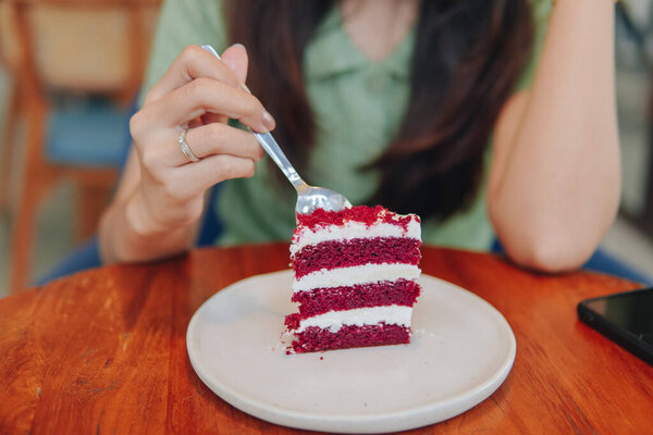A woman's hand holding spoon and cutting a slice of red velvet cake on a white plate on top of wooden table. — Stock Image Woman Hand Holding Spoon Cutting Slice Red Velvet Cake White Stock Photo