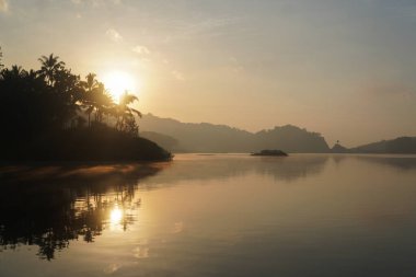 Yogyakarta 'daki Sermo Gölü üzerinde güzel bir sabah manzarası ve arka planda bir dağ..