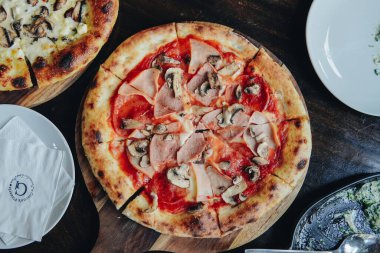 Tahtaya mantarlı ve pepperonili bir pizza. Pizza bol miktarda peynirle kaplıdır ve kıtır kıtır kıtır olur..