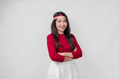 Kırmızı gömlek ve beyaz etek giyen kendine güvenen genç Asyalı kadın çapraz kollarıyla ayakta duruyor. Endonezya Bağımsızlık Günü kavramı.