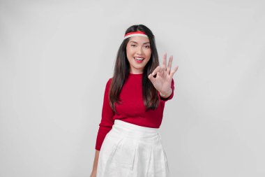 Kırmızı tişörtlü ve beyaz etekli mutlu Asyalı kadın güzel, güzel jest yapıyor. Endonezya Bağımsızlık Günü kavramı.