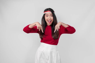 Kırmızı tişörtlü ve beyaz pantolonlu neşeli genç kadın kopya alanını gösteriyor, izole beyaz arka plan. Endonezya Bağımsızlık Günü kavramı.