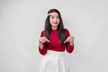 Kırmızı tişörtlü ve beyaz pantolonlu neşeli genç kadın kopya alanını gösteriyor, izole beyaz arka plan. Endonezya Bağımsızlık Günü kavramı.