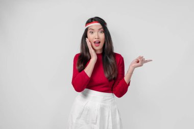 Kırmızı tişörtlü ve beyaz pantolonlu genç kadın yanındaki fotokopi odasını işaret ediyor, izole edilmiş beyaz arka plan. Endonezya Bağımsızlık Günü kavramı.