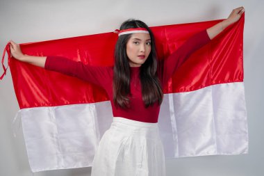 Zarif genç Asyalı kadın Endonezya bayrağını sırtında taşıyor ve manken gibi poz veriyor. Endonezya Bağımsızlık Günü konsepti.