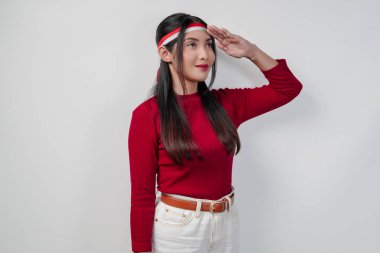 Kırmızı gömlekli ve beyaz pantolonlu güzel bir Asyalı kadın ülke bayrağına selam veriyor. Endonezya Bağımsızlık Günü kavramı.