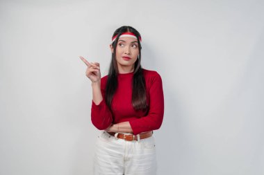 Kırmızı tişörtlü, beyaz pantolonlu, yanındaki fotokopi odasını gösteren zarif genç bir kadın, izole edilmiş beyaz bir arka plan. Endonezya Bağımsızlık Günü kavramı.