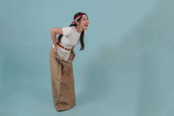 stock image Young Indonesian woman wearing gunny sack joining a competition, getting ready to jump in a sack. Indonesia Independence Day concept.