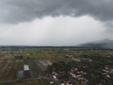 Bulutlu bir gökyüzünün portresi. Arka planda dağlar ve kırsal alan var..