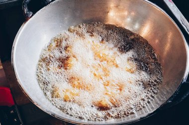 Kızarmış yemekleri pişirmek için bir tava kullanılıyor veya geleneksel Endonezya atıştırmalıkları Gorengan, pişmiş yağın üzerindeki baloncukları gösteriyor.