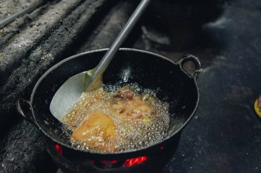 Geleneksel bir mutfakta cızırdayan yağa batırılmış tavuk eti pişirmek..