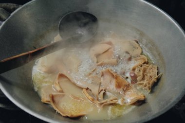 Büyük tavayı kullanarak babat veya sığır işkembesi pişiren biri. Bir yemek yapmak için kaynamış babat veya sığır işkembesi..