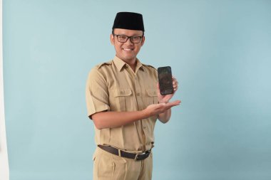 Smiling government worker man wearing khaki uniform presenting copy space on smartphone. PNS and civil servant concept.
