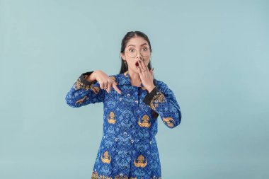 Mavi batik üniformalı ve gözlüklü bir kadın aşağıdaki fotokopi alanını işaret ediyor. PNS devlet memuru kavramı.