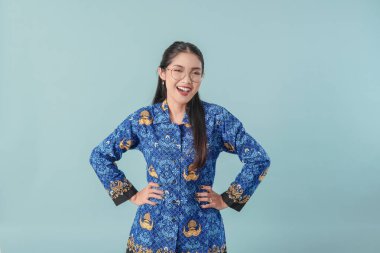 Mavi batik üniformalı ve gözlüklü, elleri kalçasında poz veren kendine güvenen bir devlet çalışanı. PNS devlet memuru kavramı.