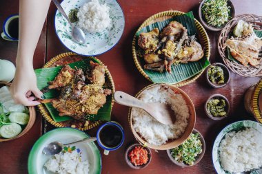 Tabaklar, kaseler ve çatallarla hazırlanmış pirinç, et ve sebzeler de dahil olmak üzere çeşitli Asya yiyecekleri içeren bir masa..