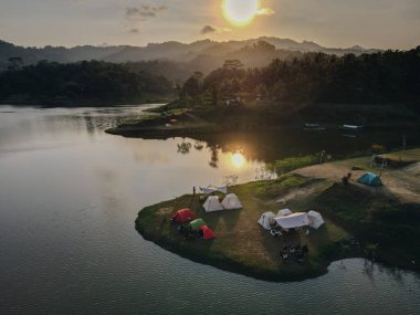 Aerial morning view of camping ground area by the Sermo Lake with forest hill on the background in Kulonprogo, Yogyakarta, Indonesia. clipart