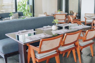 Bir restoranda yemek için içinde yeşil bitki ve gümüş vazo bulunan siyah bir yemek masası hazırlanıyor..