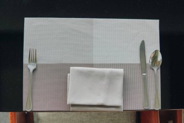 Sofraya yemek için hazırlanmış bir peçeteyle gümüş takımlar konur..