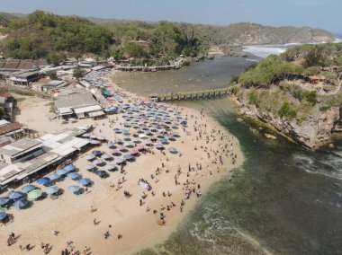 Gunungkidul, Yogyakarta, Endonezya 'daki Drini Sahili' nin havadan görünüşü. Beyaz kumlu plajlar, şemsiyeli, turistlerle dolu..