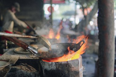 Cooking food on a stove with a lot of smoke and fire, live cooking in an open kitchen.