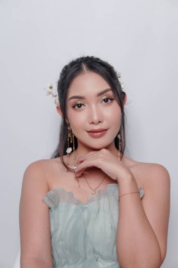 Smiling young Asian woman wearing luxurious dress and full make up over isolated white background. Beauty and make up concept.